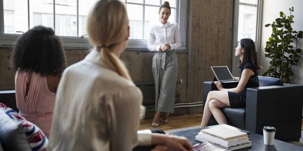 Standing female manager talking to team at casual meeting